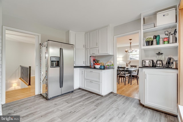 kitchen featuring dark countertops, stainless steel refrigerator with ice dispenser, white cabinetry, a chandelier, and light wood finished floors