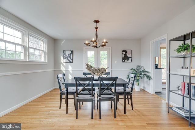 dining area featuring an inviting chandelier, baseboards, and light wood-style floors
