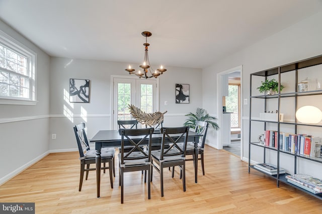 dining room featuring baseboards, light wood-style flooring, a notable chandelier, and a wealth of natural light