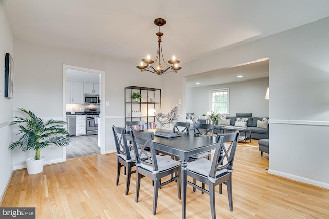 dining room with baseboards, an inviting chandelier, and light wood-style floors