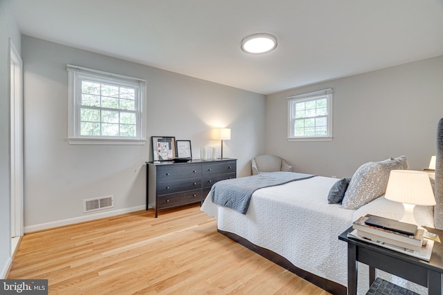 bedroom featuring baseboards, wood finished floors, and visible vents