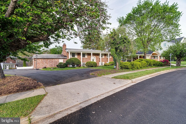 view of front of property featuring a chimney, aphalt driveway, and brick siding