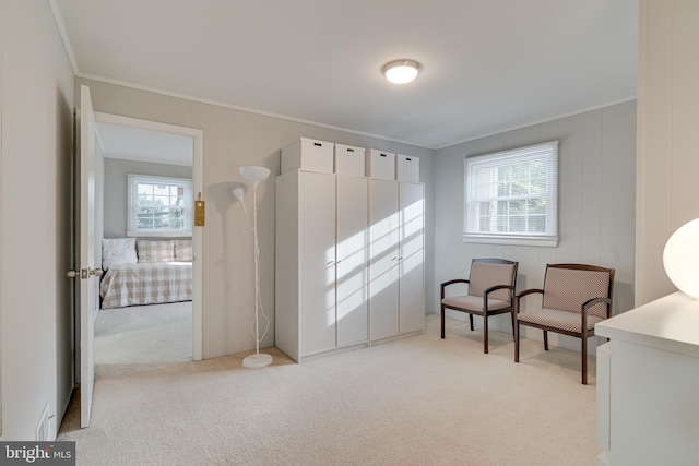 living area with crown molding and light colored carpet