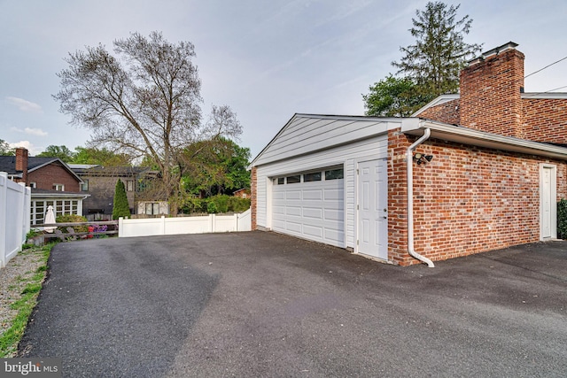 garage with fence and aphalt driveway