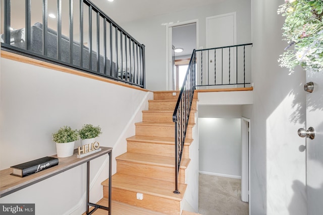 staircase featuring baseboards and carpet