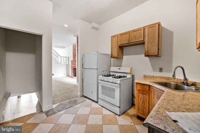 kitchen with white appliances, a sink, light countertops, brown cabinets, and light tile patterned floors