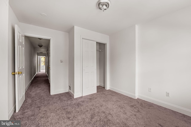 unfurnished bedroom with carpet floors, baseboards, and a closet