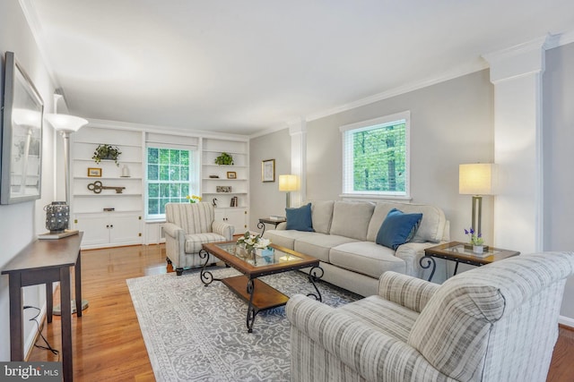 living room with crown molding, ornate columns, built in shelves, and light wood finished floors