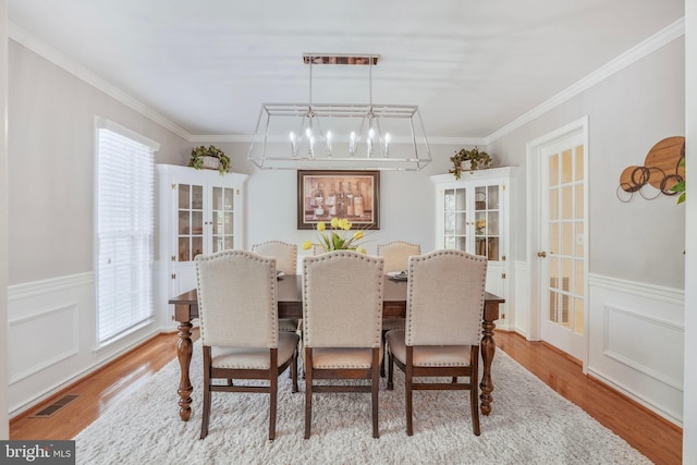 dining room with crown molding, a healthy amount of sunlight, and an inviting chandelier