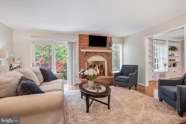 living area with a brick fireplace and wood finished floors