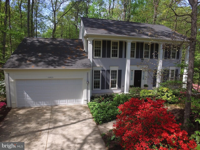 view of front of property featuring driveway, roof with shingles, and a garage