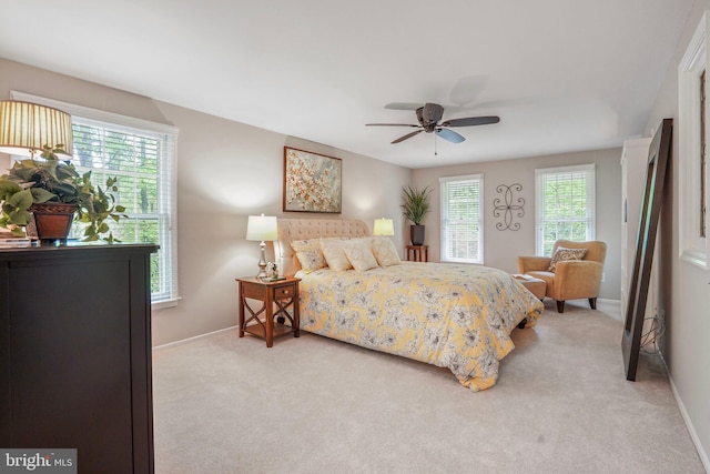bedroom with baseboards, multiple windows, and light colored carpet