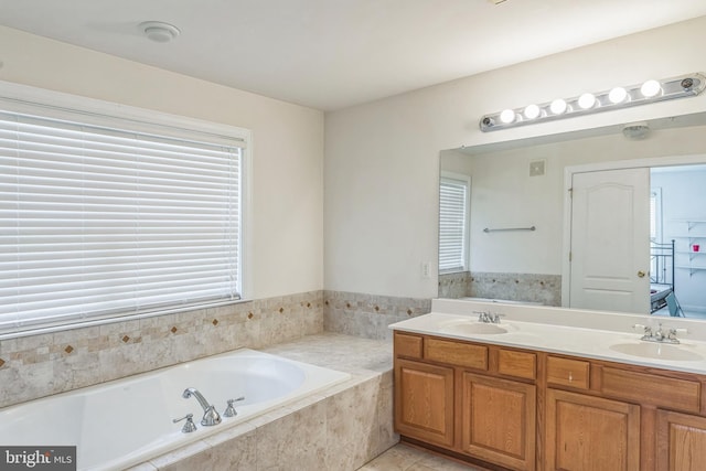 full bathroom featuring a sink, tile patterned floors, a garden tub, and double vanity