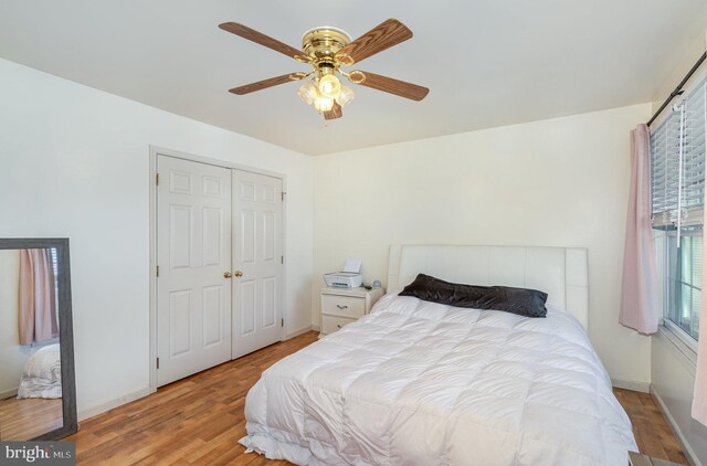 bedroom featuring baseboards, ceiling fan, wood finished floors, and a closet