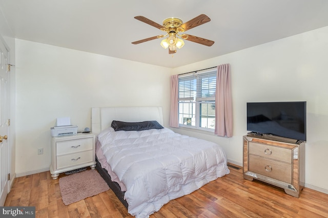 bedroom featuring baseboards, ceiling fan, and light wood-style flooring