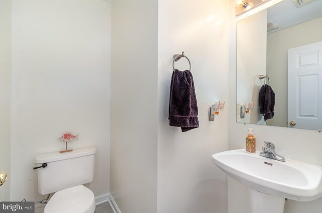 half bath featuring baseboards, a sink, and toilet