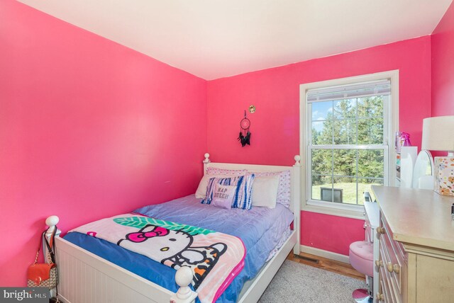 bedroom with light wood-type flooring, baseboards, visible vents, and multiple windows