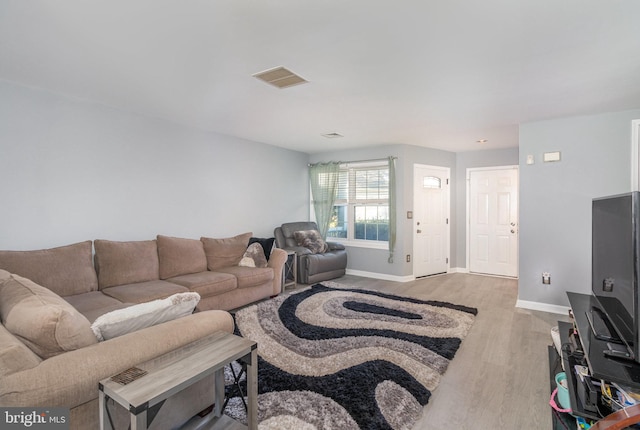 living room with baseboards, visible vents, and wood finished floors