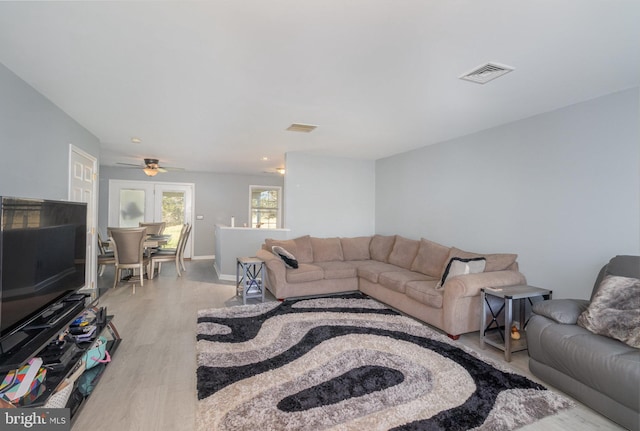 living area featuring a ceiling fan, baseboards, visible vents, and light wood-style flooring