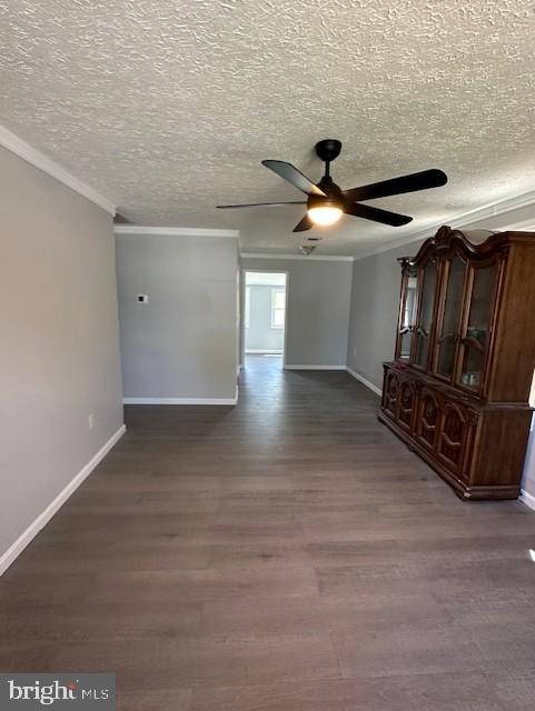 unfurnished living room with ceiling fan, a textured ceiling, crown molding, dark wood finished floors, and baseboards
