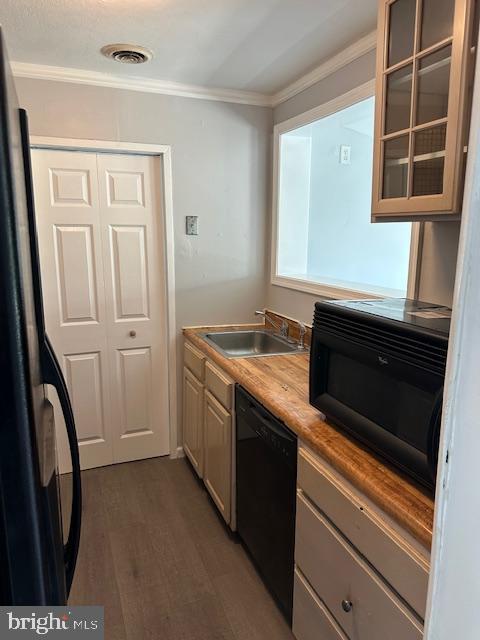 kitchen with ornamental molding, wood finished floors, glass insert cabinets, a sink, and black appliances