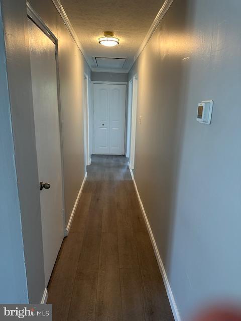 hall with crown molding, attic access, baseboards, and wood finished floors