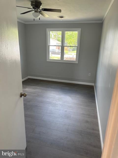 unfurnished room featuring crown molding, baseboards, a ceiling fan, and dark wood finished floors