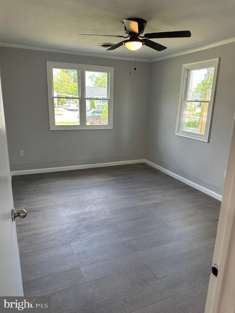 empty room with baseboards, ornamental molding, and wood finished floors
