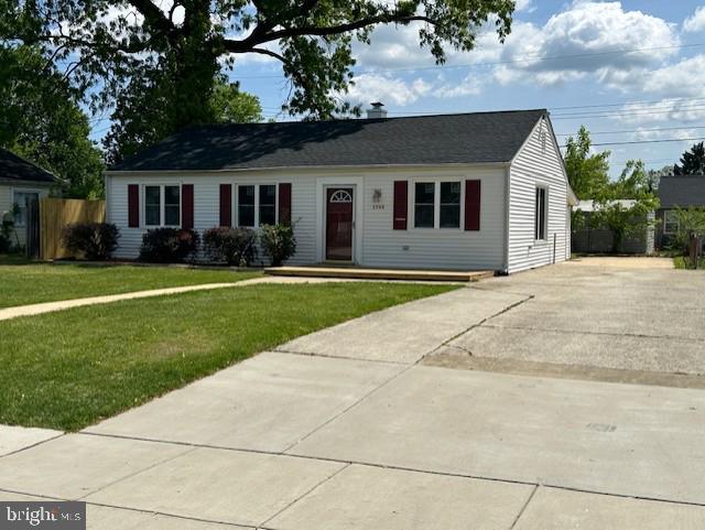 ranch-style home with fence, concrete driveway, and a front lawn