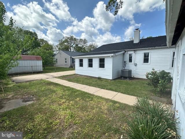 rear view of house featuring a chimney and a yard