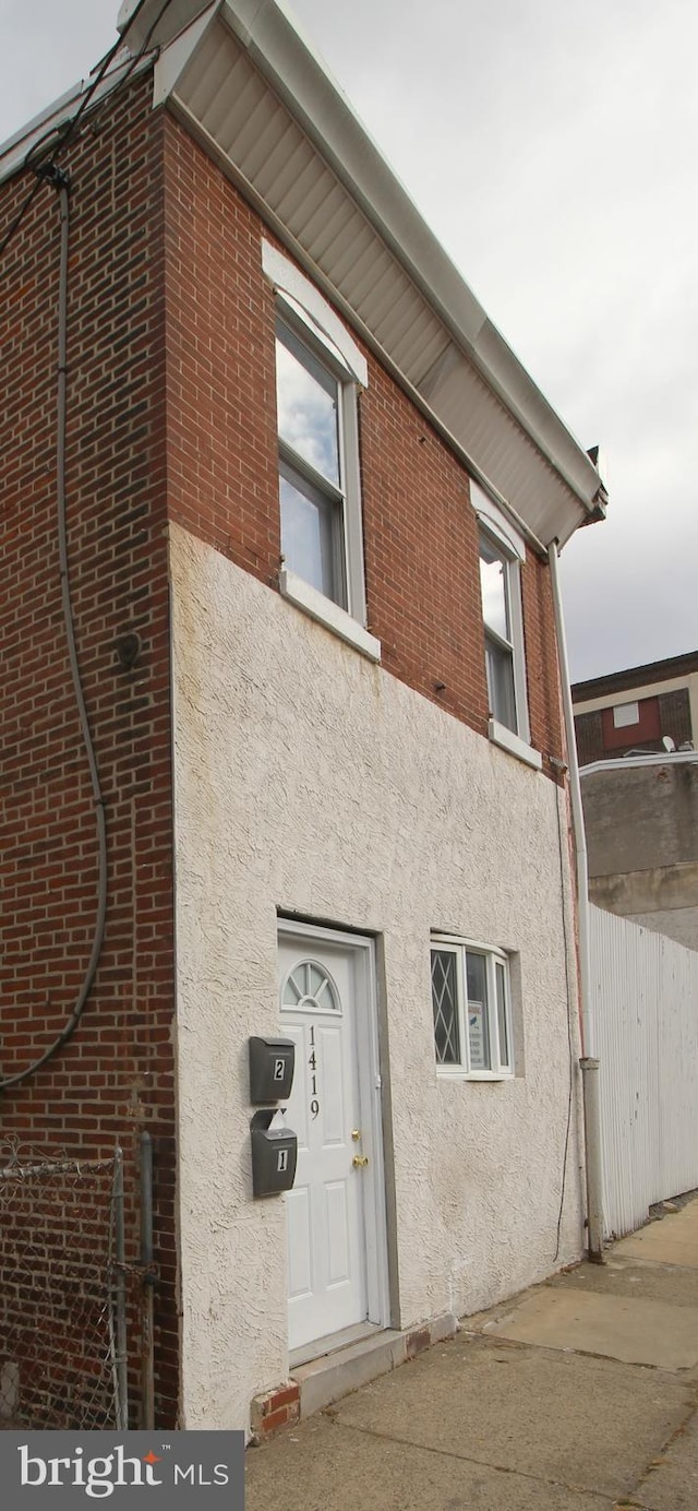 exterior space with stucco siding and brick siding