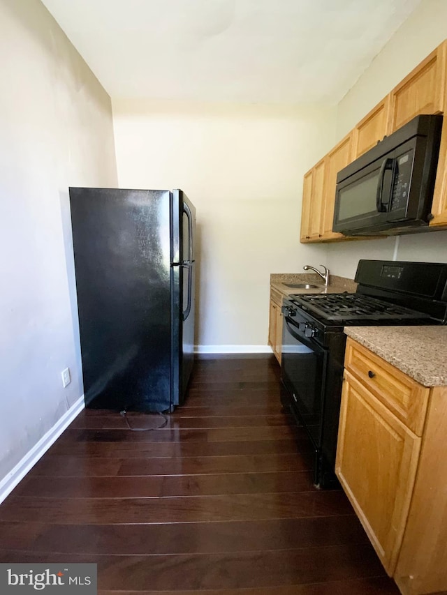 kitchen featuring dark wood-style flooring, light stone countertops, a sink, baseboards, and black appliances