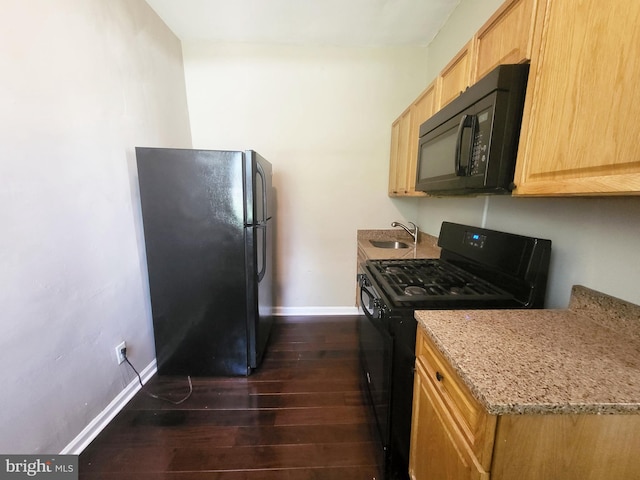 kitchen with light stone counters, a sink, baseboards, dark wood-type flooring, and black appliances