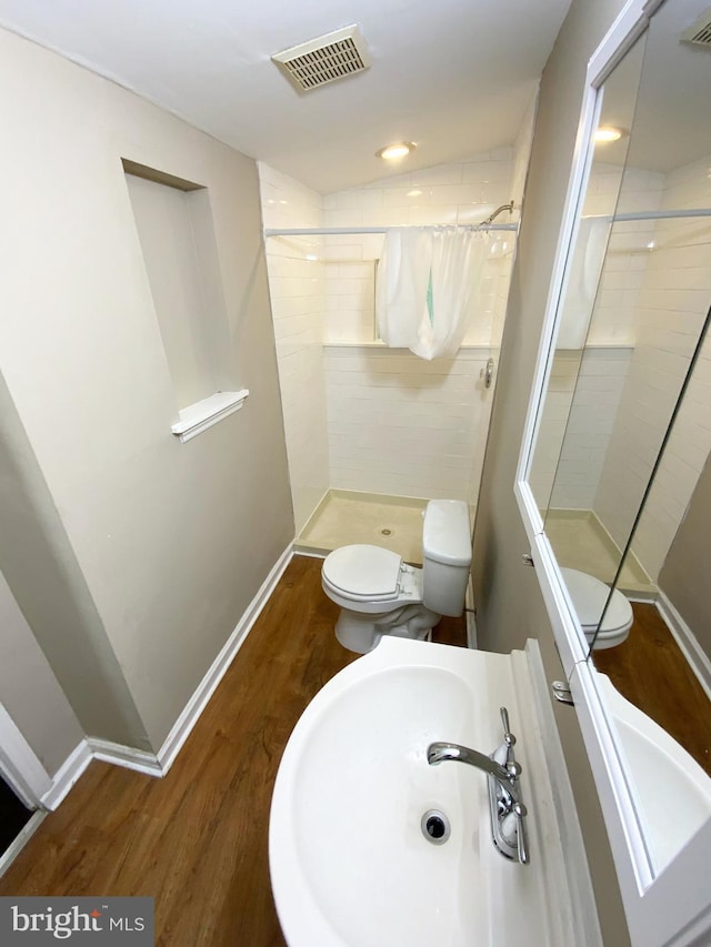 bathroom with visible vents, wood finished floors, toilet, baseboards, and a shower stall