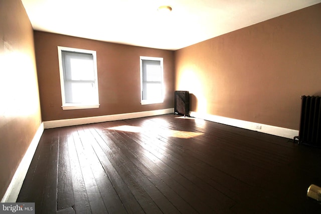 empty room featuring baseboards, radiator, and dark wood-style flooring
