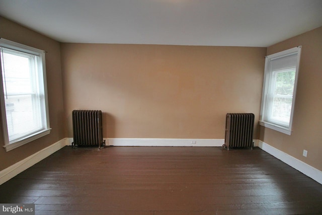 spare room featuring radiator, baseboards, and dark wood-style flooring