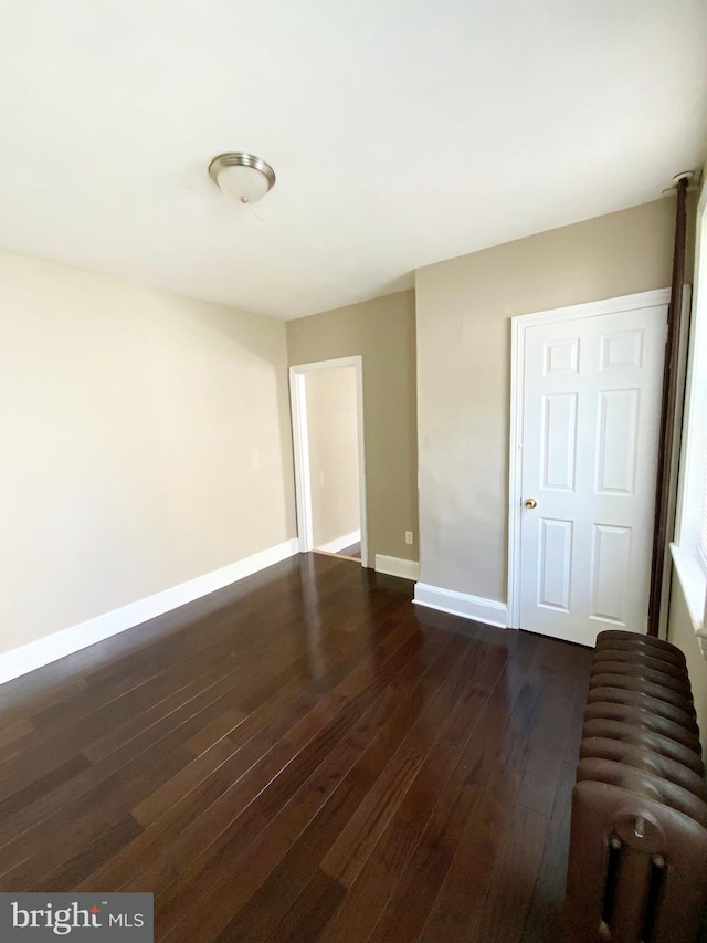 empty room featuring dark wood-style flooring and baseboards