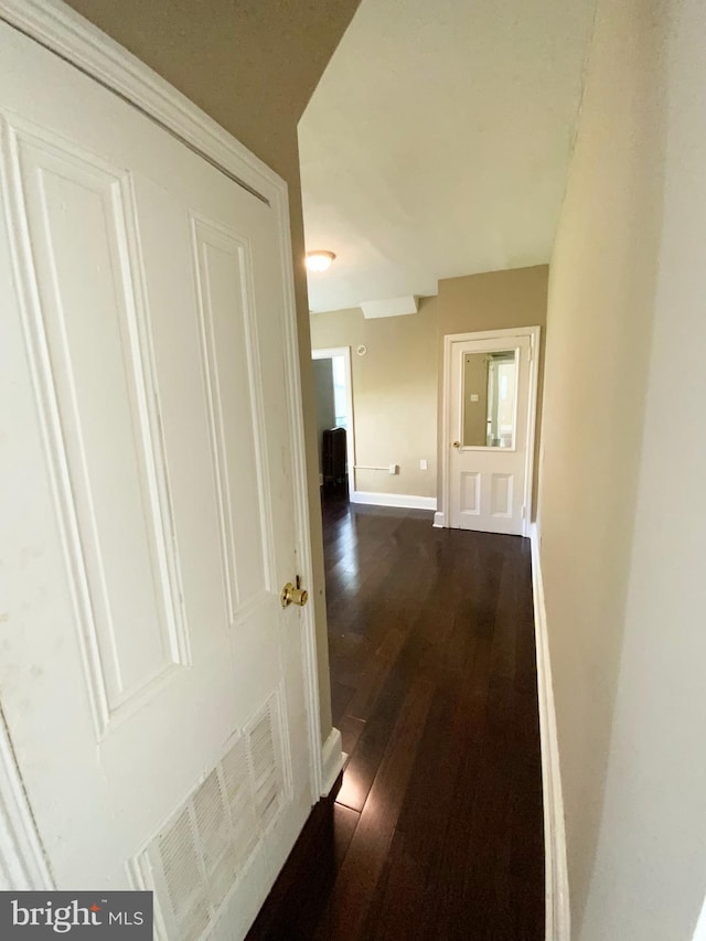 corridor featuring baseboards, visible vents, and dark wood-type flooring