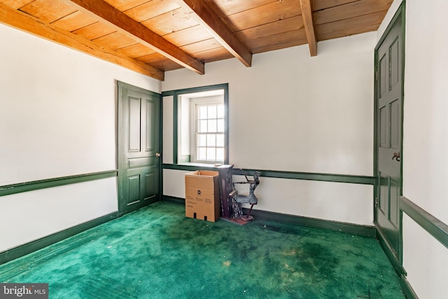 carpeted empty room featuring baseboards, beam ceiling, and wood ceiling
