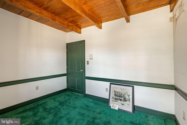 carpeted empty room featuring wood ceiling, baseboards, and beam ceiling