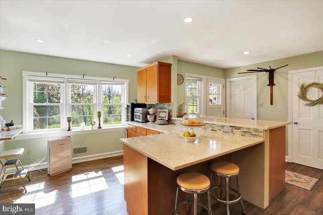 kitchen with a peninsula, visible vents, dark wood-style floors, and a wealth of natural light