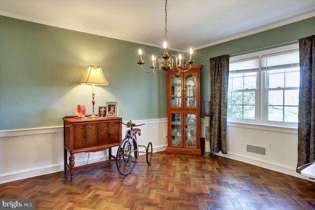 dining room with crown molding, a notable chandelier, wainscoting, baseboards, and visible vents