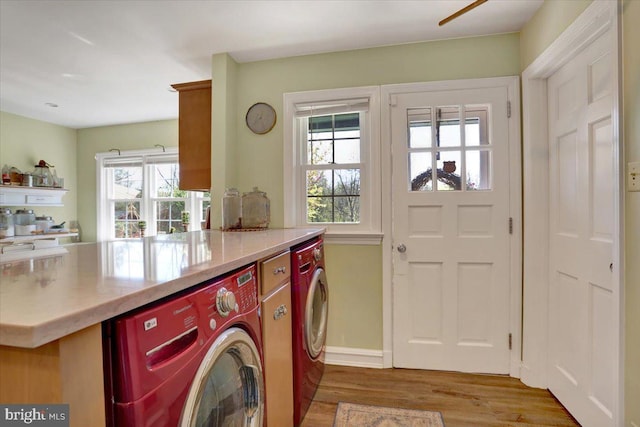 washroom with laundry area, washing machine and dryer, light wood finished floors, and a wealth of natural light