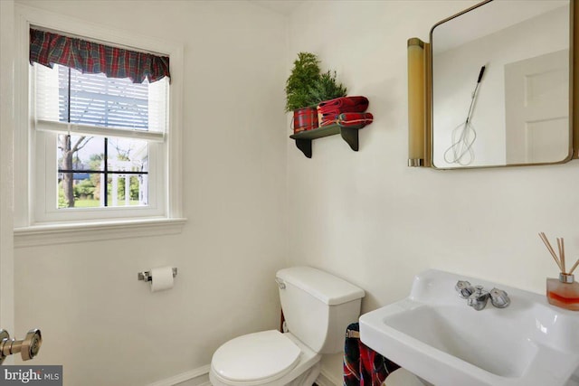 bathroom featuring toilet, baseboards, and a sink