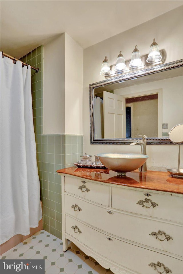 full bathroom with a shower with curtain, tile walls, and vanity