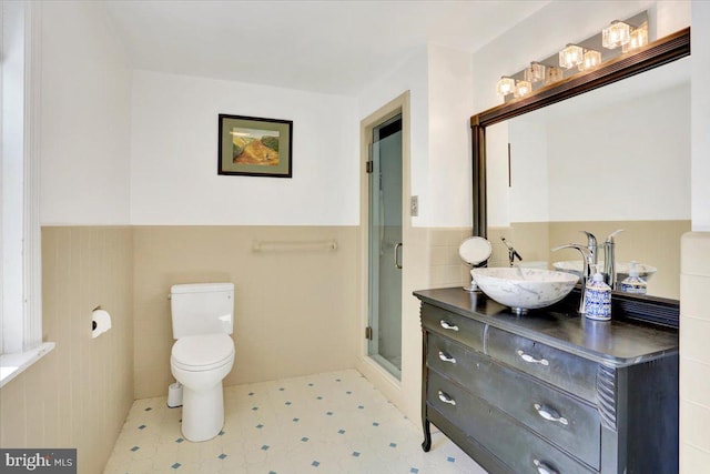 bathroom featuring tile walls, a shower stall, wainscoting, vanity, and tile patterned floors