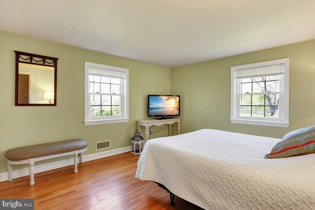 bedroom featuring baseboards, visible vents, and wood finished floors