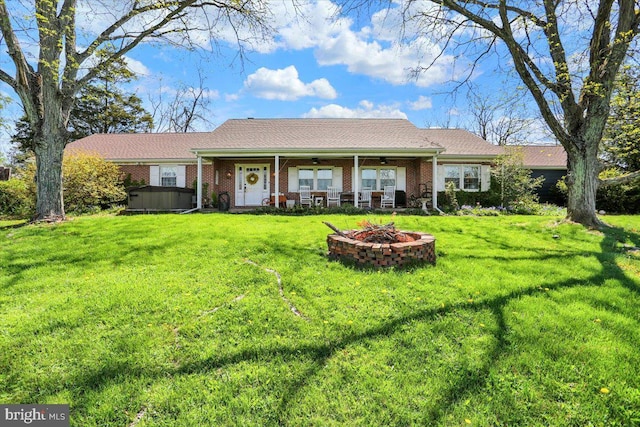ranch-style home featuring brick siding, a ceiling fan, a fire pit, and a front yard