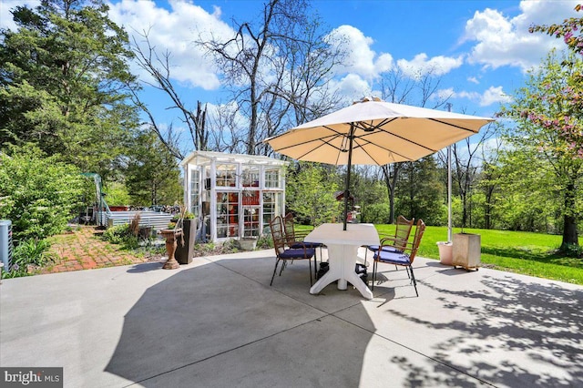 view of patio / terrace featuring a greenhouse, an outbuilding, and outdoor dining space