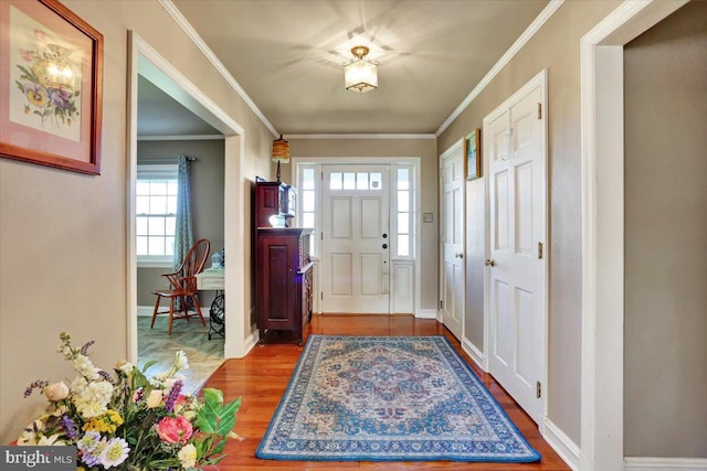 entryway featuring crown molding, plenty of natural light, and wood finished floors